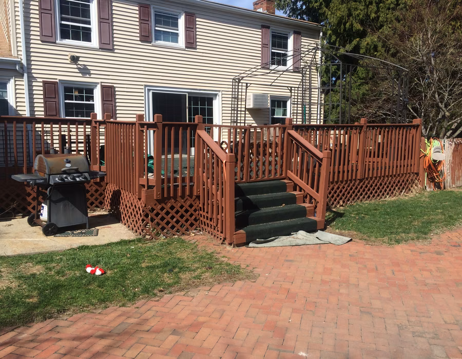 Backyard deck with reddish wood railings and central stairs