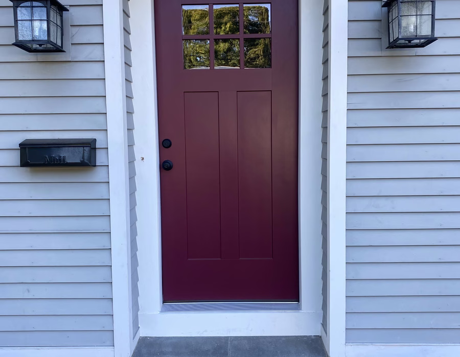 Front entry with a burgundy glass-paneled door and white trim