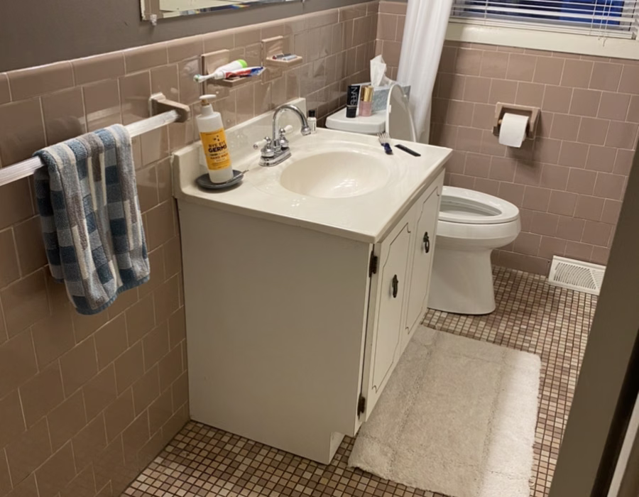 Bathroom with a white vanity, tan tiled walls, and mosaic flooring