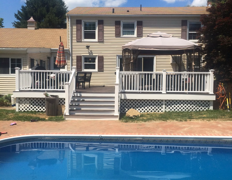 Backyard deck with white railings and stairs beside a pool