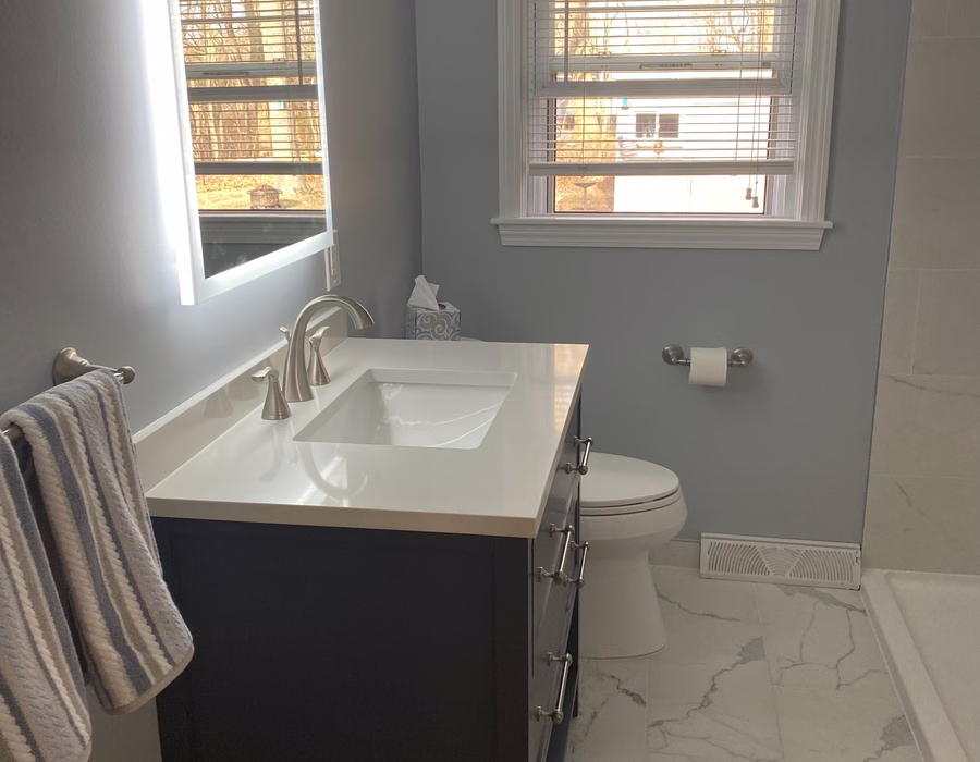 Bathroom with a dark vanity, rectangular sink, and light tile flooring